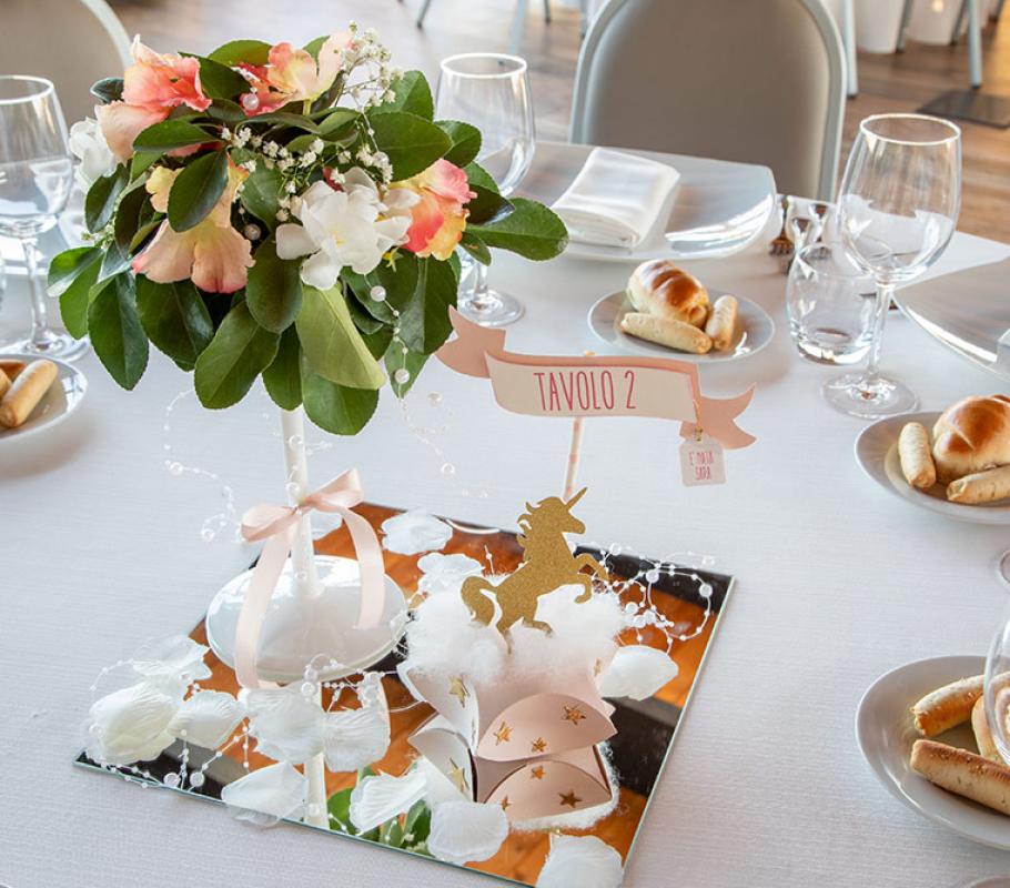 Tavola elegante con fiori vivaci, unicorno dorato, atmosfera magica e accogliente.